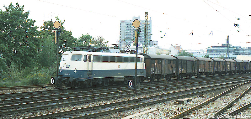 Die B&uuml;gelfalten-110 437-1 kommt mit einem G&uuml;terzug vom Rangierbahnhof M&uuml;nchen-Laim (M&uuml;nchen Heimeranplatz, August 1990)