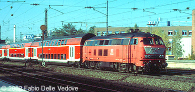 Die orientrote 218 444-8 vor einem verkehrsroten Dosto-Zug nach M&uuml;hldorf (M&uuml;nchen Heimeranplatz, Oktober 2001)