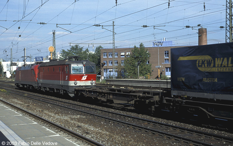 182 011-7 hat 1044 238-2 und einen Zug aus Einheitstaschenwagen im Schlepp, als sie um 11:05 Uhr in Richtung Laim unterwegs ist (M&uuml;nchen Heimeranplatz, Oktober 2002).