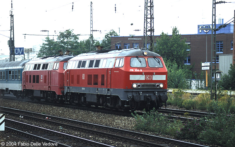 Die verkehrsrote 218 354-9 und eine orientrote 218 vor RB 31463 (M&uuml;nchen Hbf 15:14 - M&uuml;nchen Ost 15:22 - M&uuml;hldorf (Obb) - 16:19/16:28 - Simbach (Inn) 16:59) um 15:17 Uhr (M&uuml;nchen Heimeranplatz, September 2003).